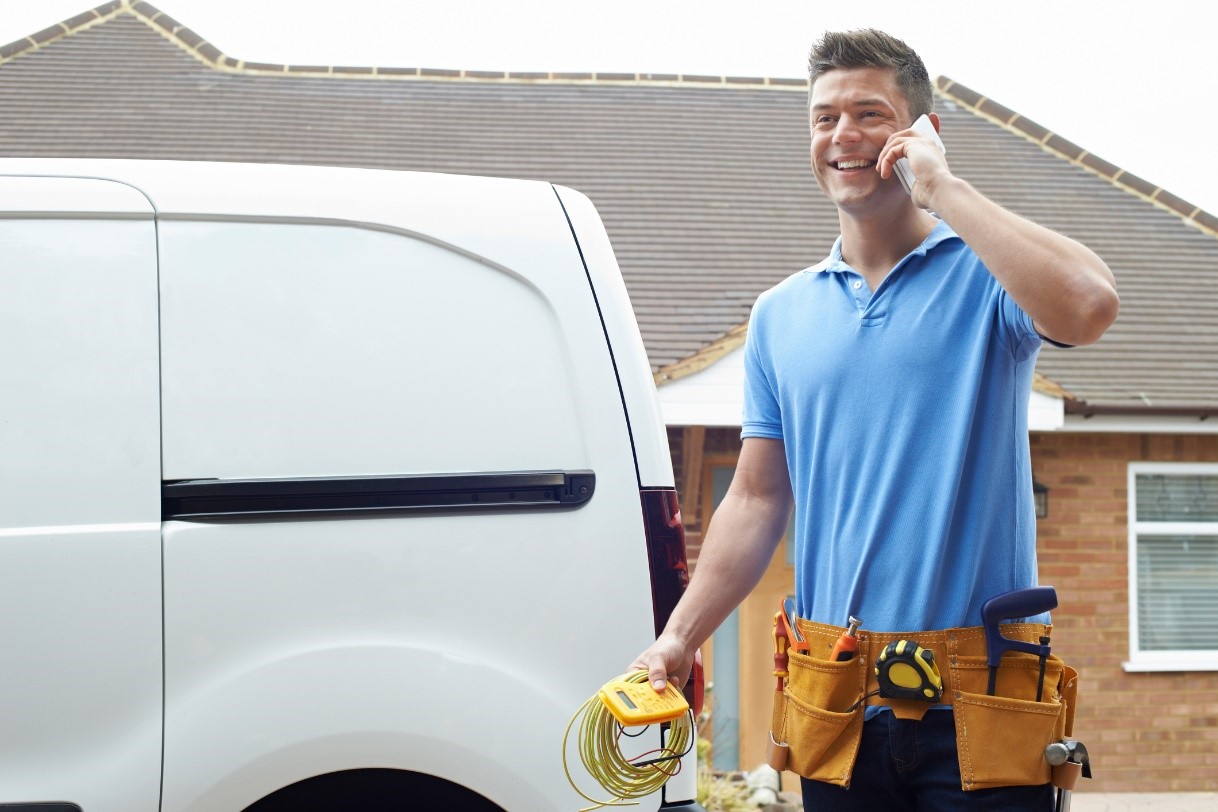 Technician on the phone in front of a white work van