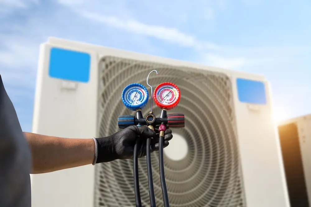 hvac technician using manifold gauge to check and fill refrigerant