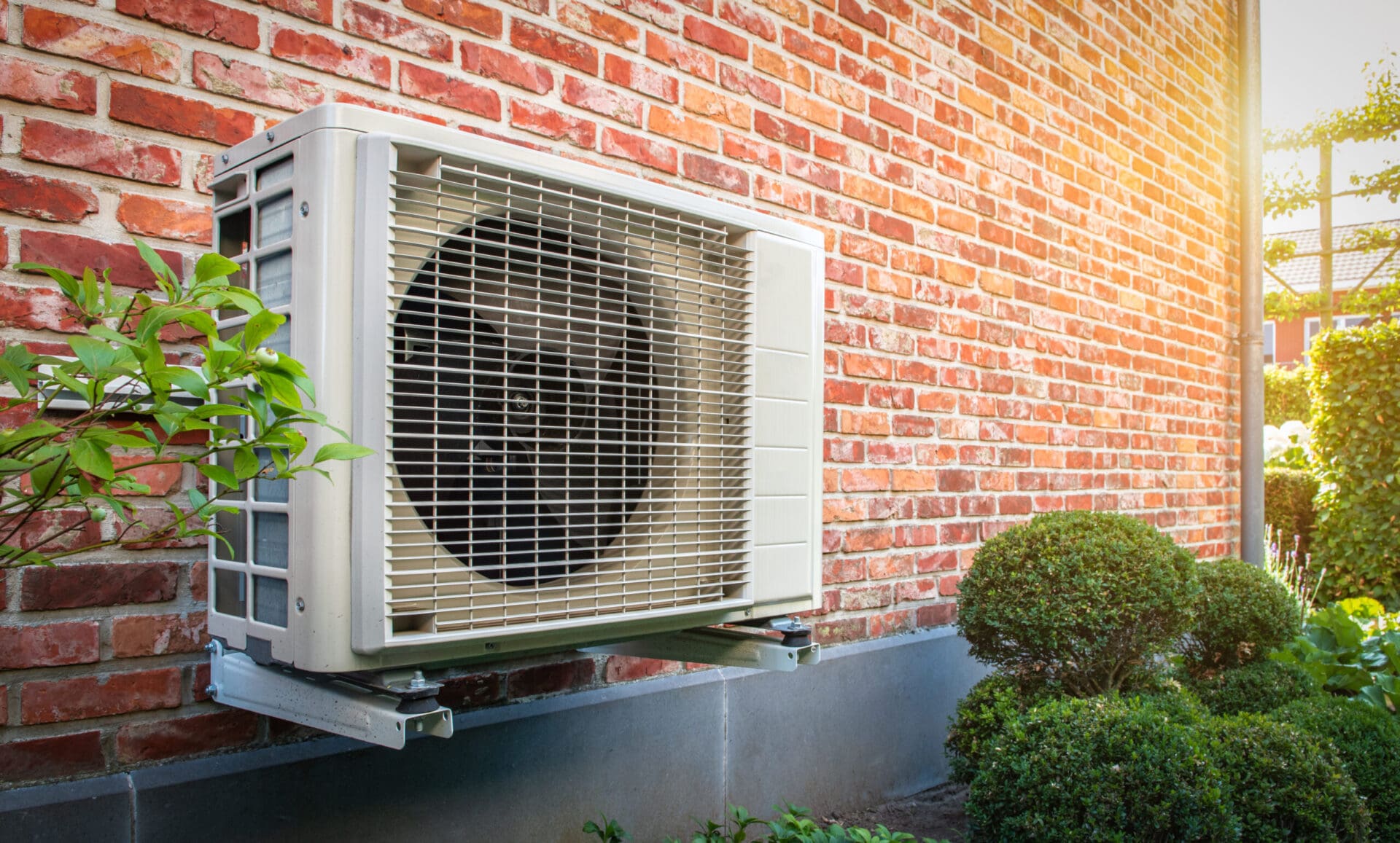 Heat pump unit mounted outside a home on brick wall